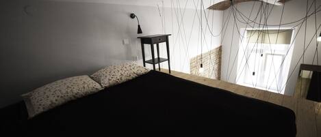 A bedroom with a bed, a nightstand, and a window with curtains.