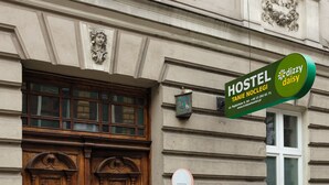 A building with a large wooden double door and a sign indicating it is a hostel. - Dizzy Daisy Hostel (Kraków)