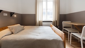 A bedroom with a bed, a small table, and a chair. - Dizzy Daisy Hostel (Kraków)