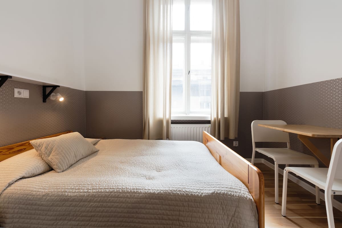 A bedroom with a bed, a small table, and a chair.