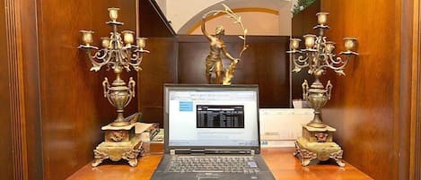 Una computadora portátil sobre un escritorio de madera con candelabros ornamentados a cada lado.
