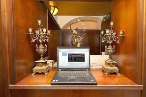 A laptop on a wooden desk with ornate candelabras on either side. - Hotel Antik (Prague)