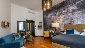 Moderni hotellihuone, jossa on suuri sänky, sohva, pieni pöytä ja tuoli.