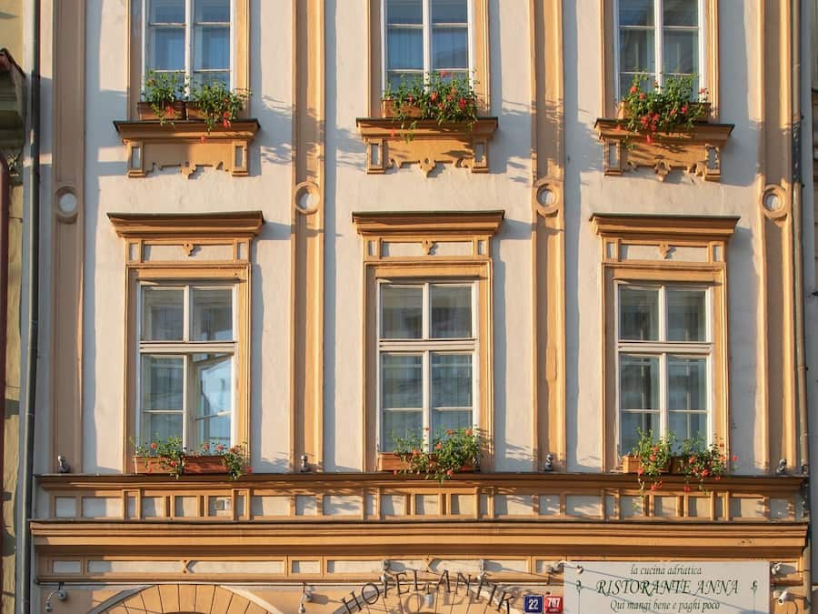 Um edifício histórico com várias janelas, entrada central e placas com os dizeres 'Hotel' e 'Ristorante Anna'.