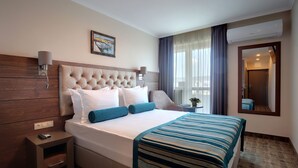 Ein Hotelzimmer mit einem großen Bett, einem Nachttisch, einer Wandlampe, einem Gemälde und einem Spiegel.