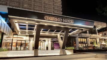 El exterior del hotel Cherno More, con un diseño moderno, que presenta una entrada destacada y señalización iluminada.