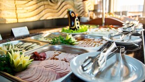 Ein Buffet mit verschiedenen Speisen, darunter Aufschnitt, Gemüse und einer dekorativen Pinguin-Figuren-Mitteldeeoration.