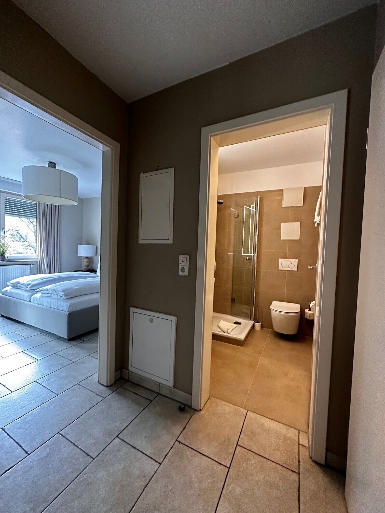 Hotellihuone, jossa on sänky, yöpöytä, lamppu, suihku ja wc.