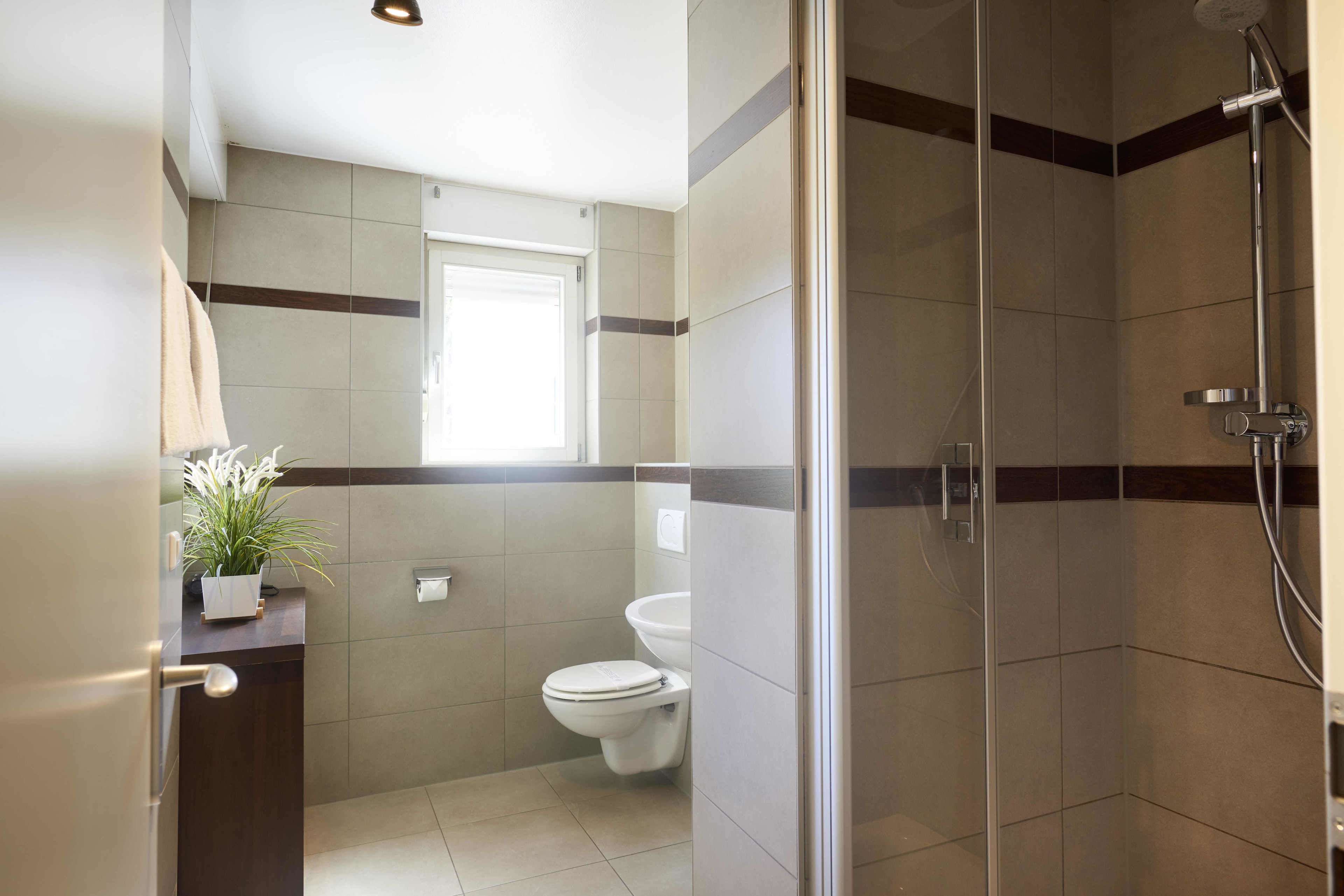 Un baño con inodoro, lavamanos y zona de ducha.