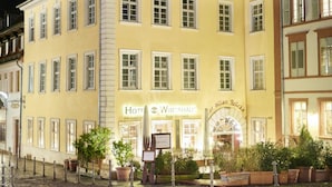 Un edificio amarillo con varias ventanas y un letrero que dice 'Hotel Wirtshaus Zur Alten Brücke'.