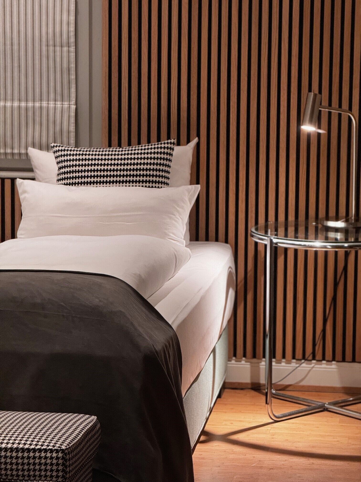 Un dormitorio moderno con una cama, almohadas, una mesita de noche y una silla.