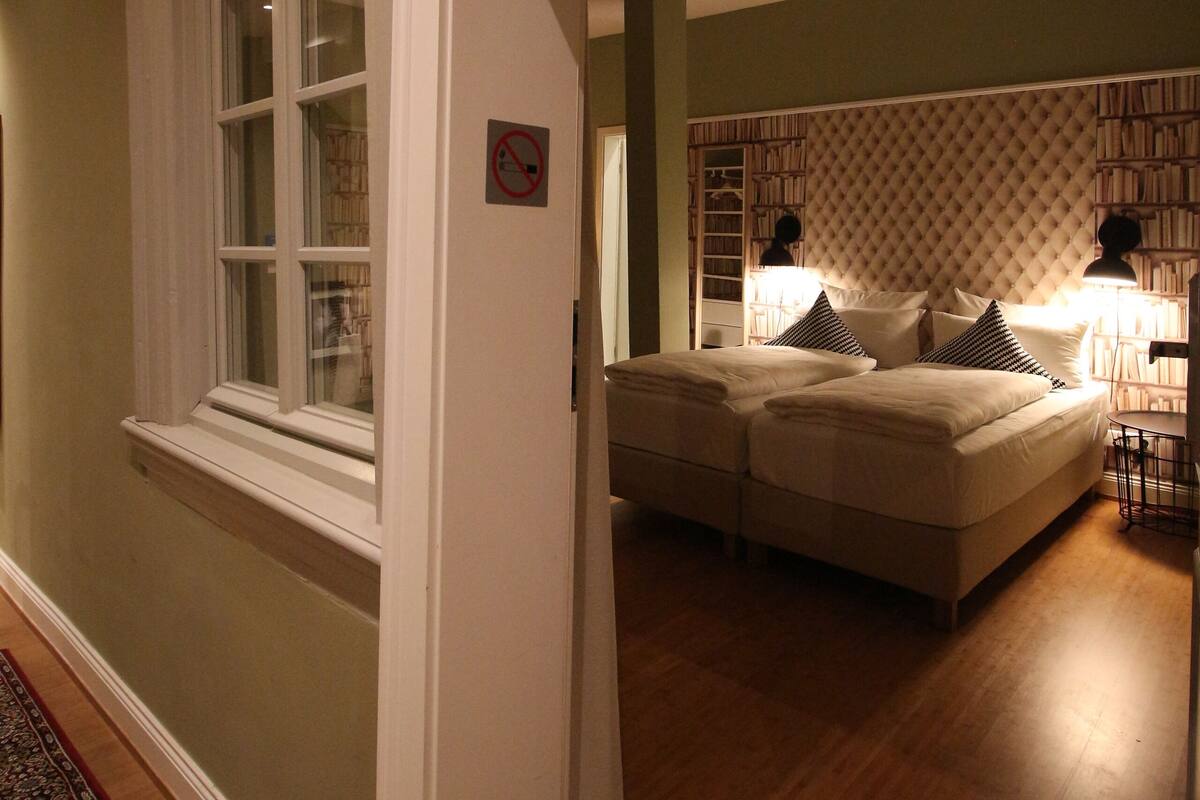 A bedroom with a large bed, a nightstand, and a reading lamp.