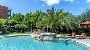 A swimming pool with clear water, surrounded by red umbrellas and white lounge chairs. - Servotel Saint-Vincent (Nice)