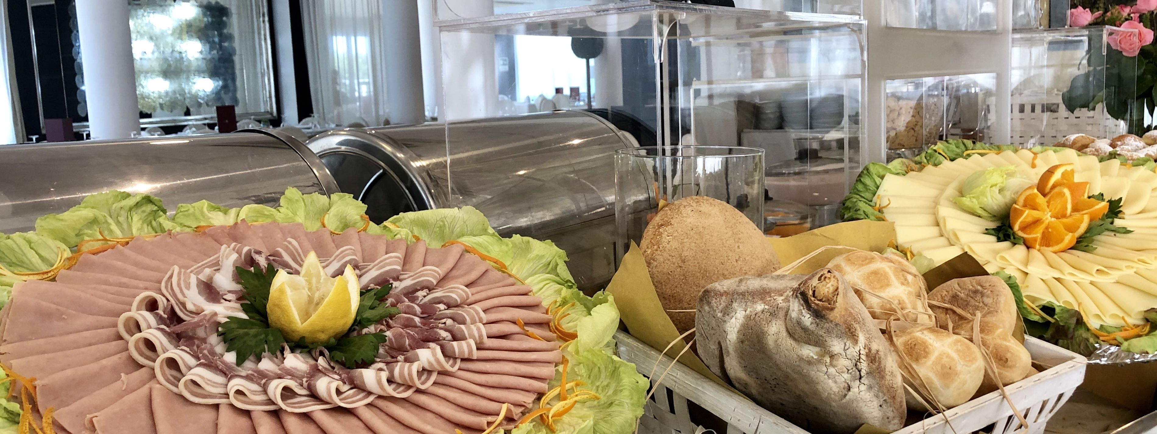 Un bufé con diversas opciones de comida, incluyendo carnes, quesos y panes.