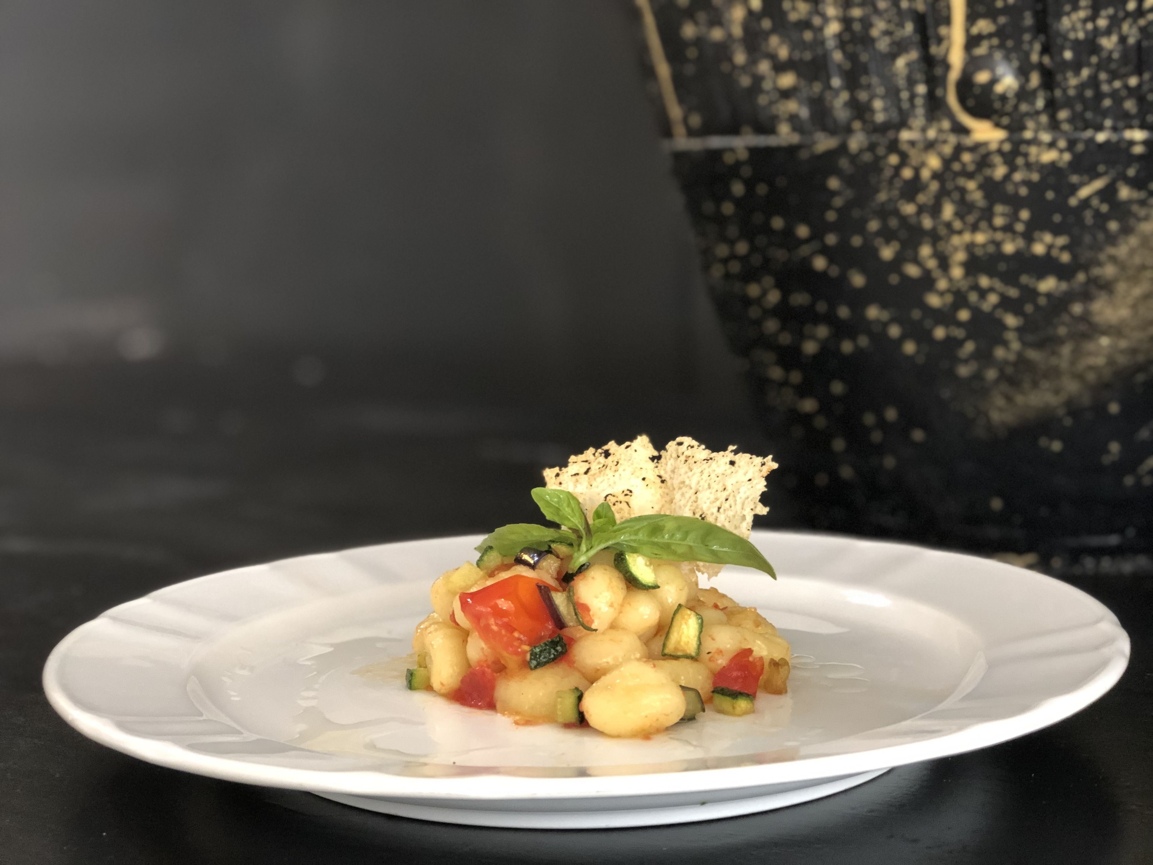 A white plate with a food dish, a black bag, and a dark background.