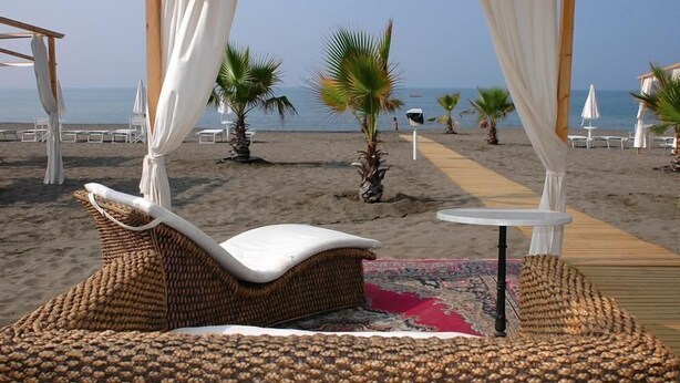 Een strandlounge met rieten meubels, een tafeltje en uitzicht op zee.