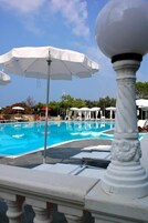 Una piscina al aire libre, sillones reclinables de piscina