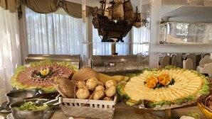 Een buffet met diverse etenswaren, waaronder een decoratie van een schip, brood, kaas en fruit.