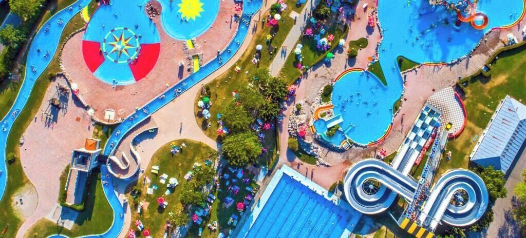 Vista aérea de un parque acuático con múltiples piscinas, toboganes y una zona circular central con diseño de estrella.