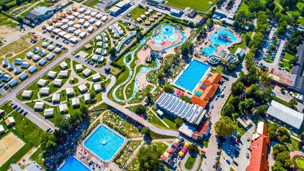 Vista aérea de un complejo turístico con varias piscinas, parque acuático y un amplio estacionamiento.