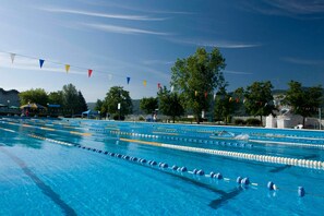 A swimming pool with multiple lanes, trees, and a clear sky. - Hotel Toplice (Brezice)