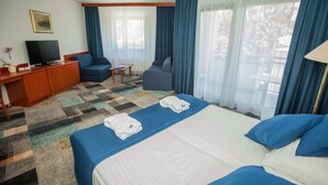 Una habitación de hotel con una cama grande, dos sillones, un televisor y un escritorio.