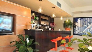 A modern reception area with a bar, seating, and a TV. - Inn Hotel (Barberino di Mugello)