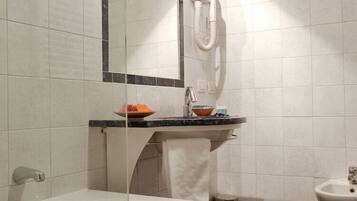 Un baño con bañera, lavamanos con espejo y bidé.