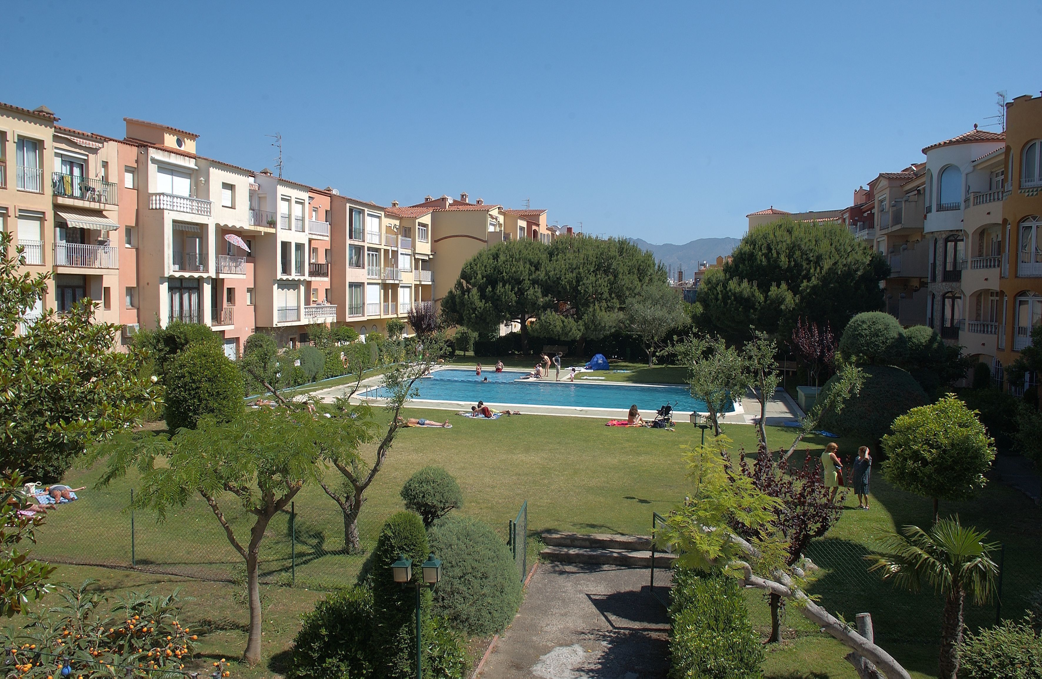 Un conjunto residencial con piscina rodeado de vegetación y varios edificios de apartamentos.