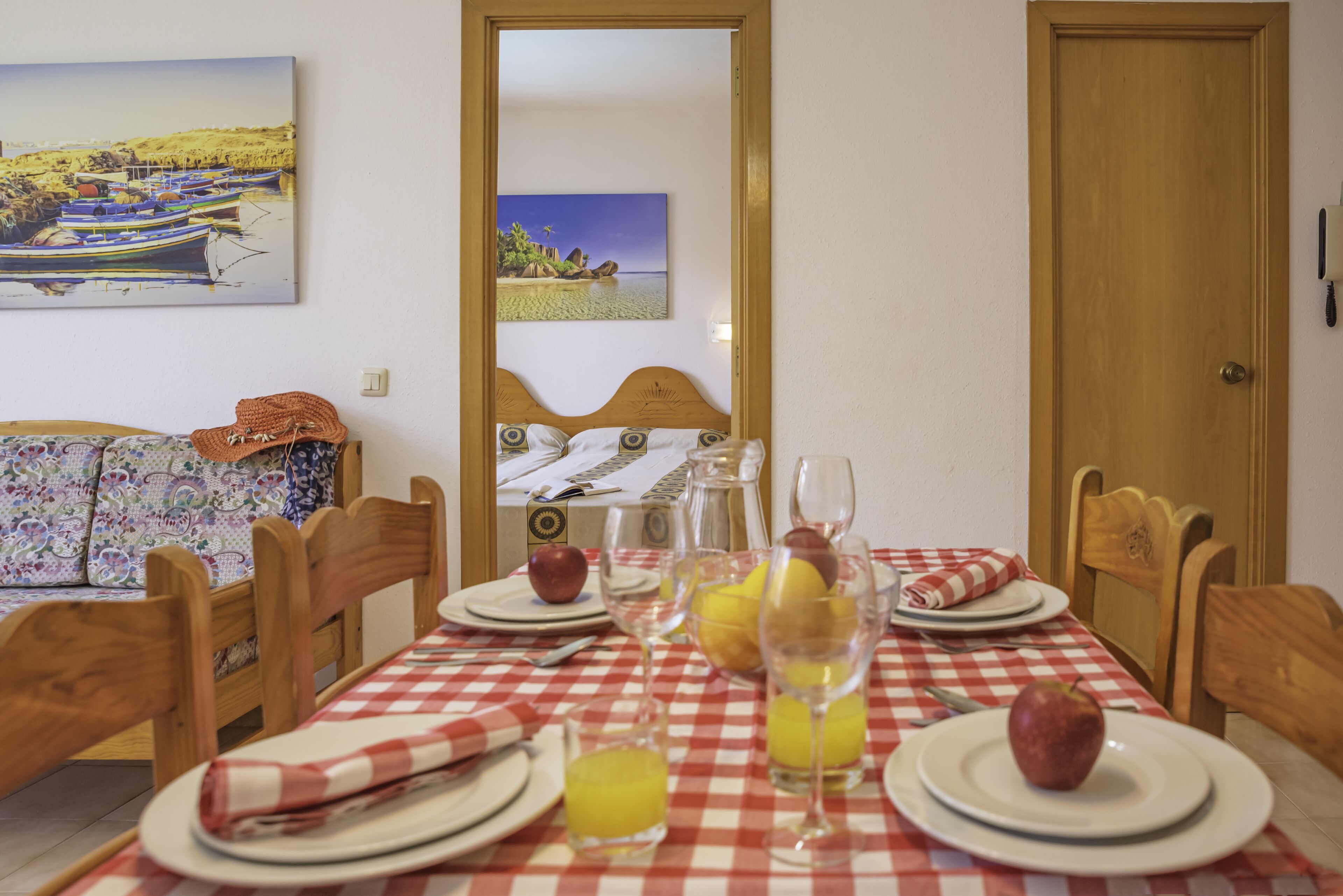 A dining table set with plates, glasses, and fruits, with a checkered tablecloth.