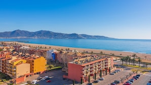 A coastal hotel with multiple floors, a parking lot, and a view of the beach and ocean. - Apartaments Comte d'Empuries (Castello d'Empuries)