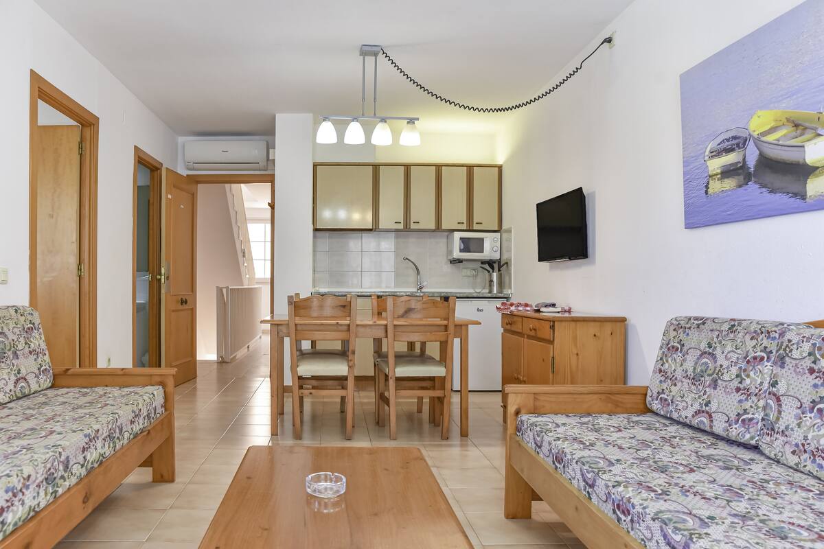 A compact living space with a kitchenette, wooden furniture, and a painting on the wall.