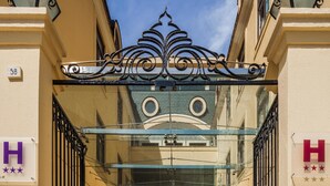 A hotel entrance with a glass canopy, metal gates, and a clear sky. - Hotel Boa-Vista (Porto)