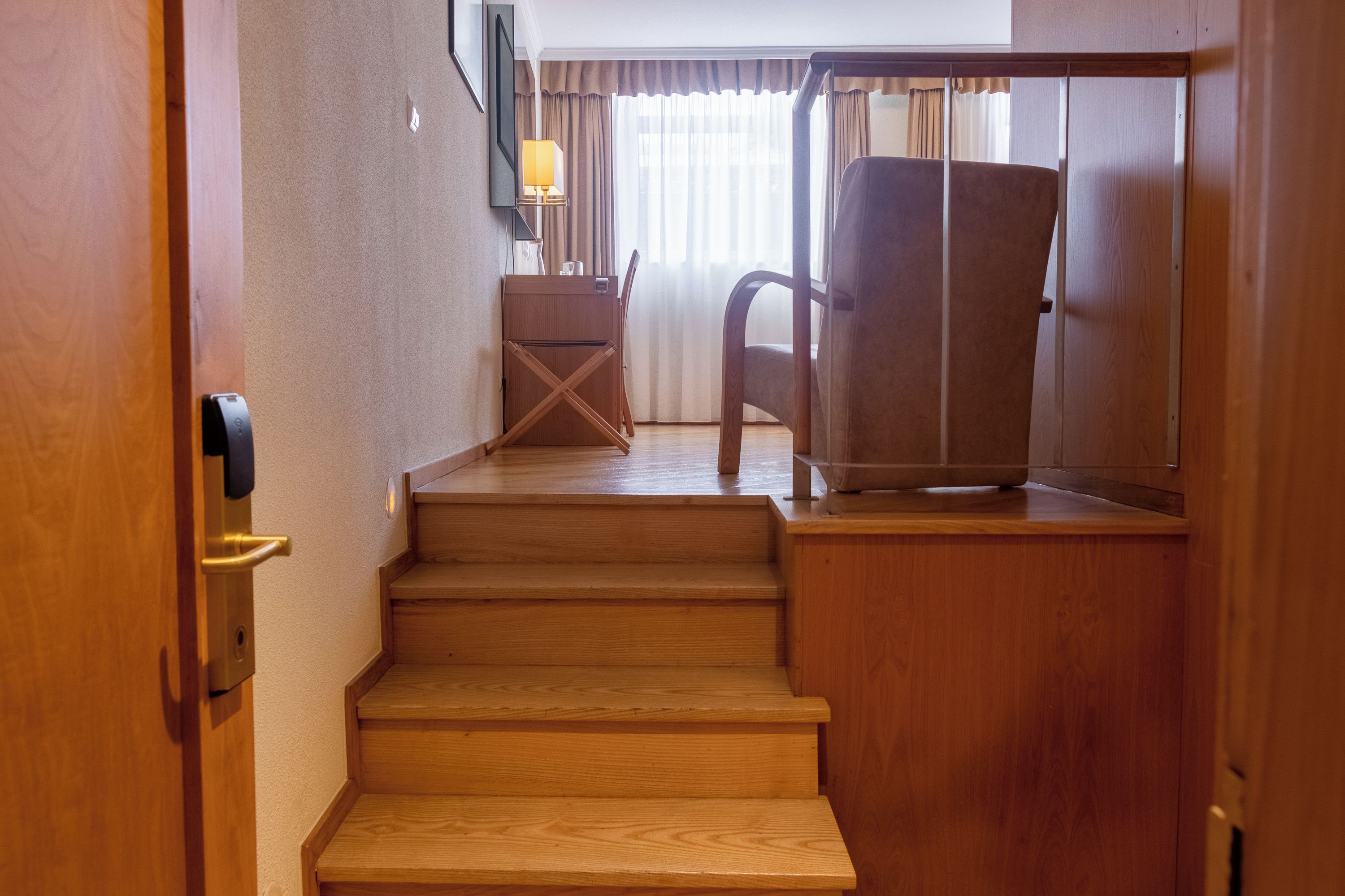 A wooden staircase leading to a room with a chair and a desk.