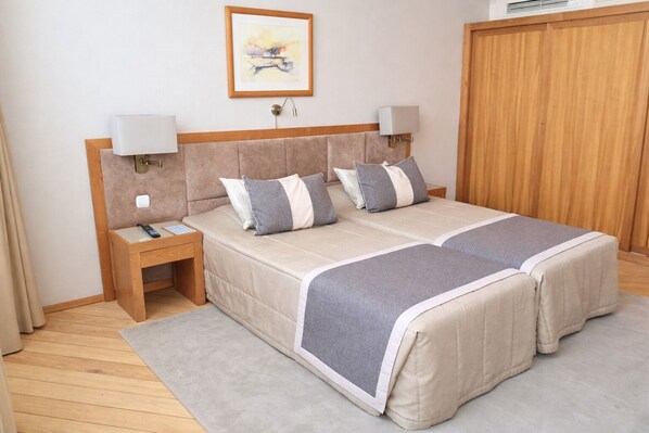 A double bed with a headboard, bedside tables, a nightstand, a framed picture, and a wooden wardrobe. - Hotel Boa-Vista (Porto)