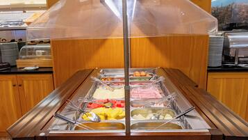 Disposição de buffet com diversos alimentos e utensílios.