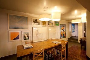 A dining area with a wooden table and chairs, framed artwork on the walls, and pendant lighting. -  Stay Hotel Porto Centro Antas (Porto)