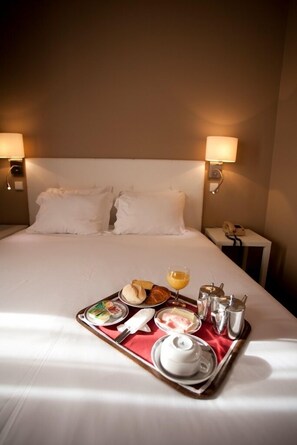 A hotel room with a neatly made bed, a tray with breakfast items, and bedside lamps. -  Stay Hotel Porto Centro Antas (Porto)