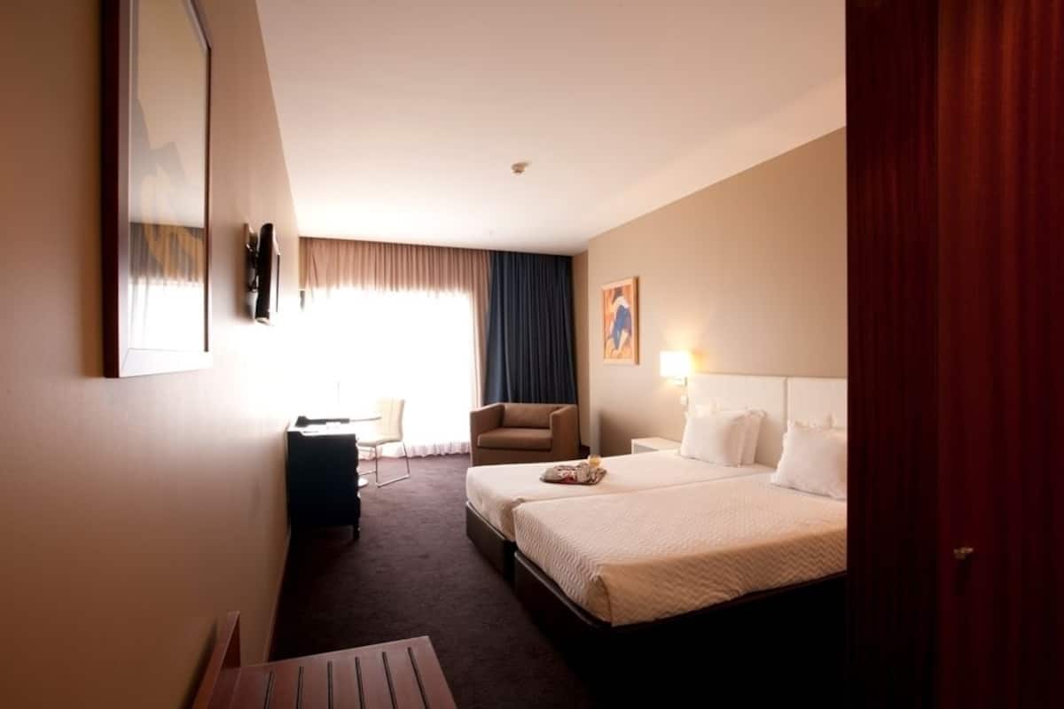 Una habitación de hotel con una cama grande, un escritorio, una silla y un armario.