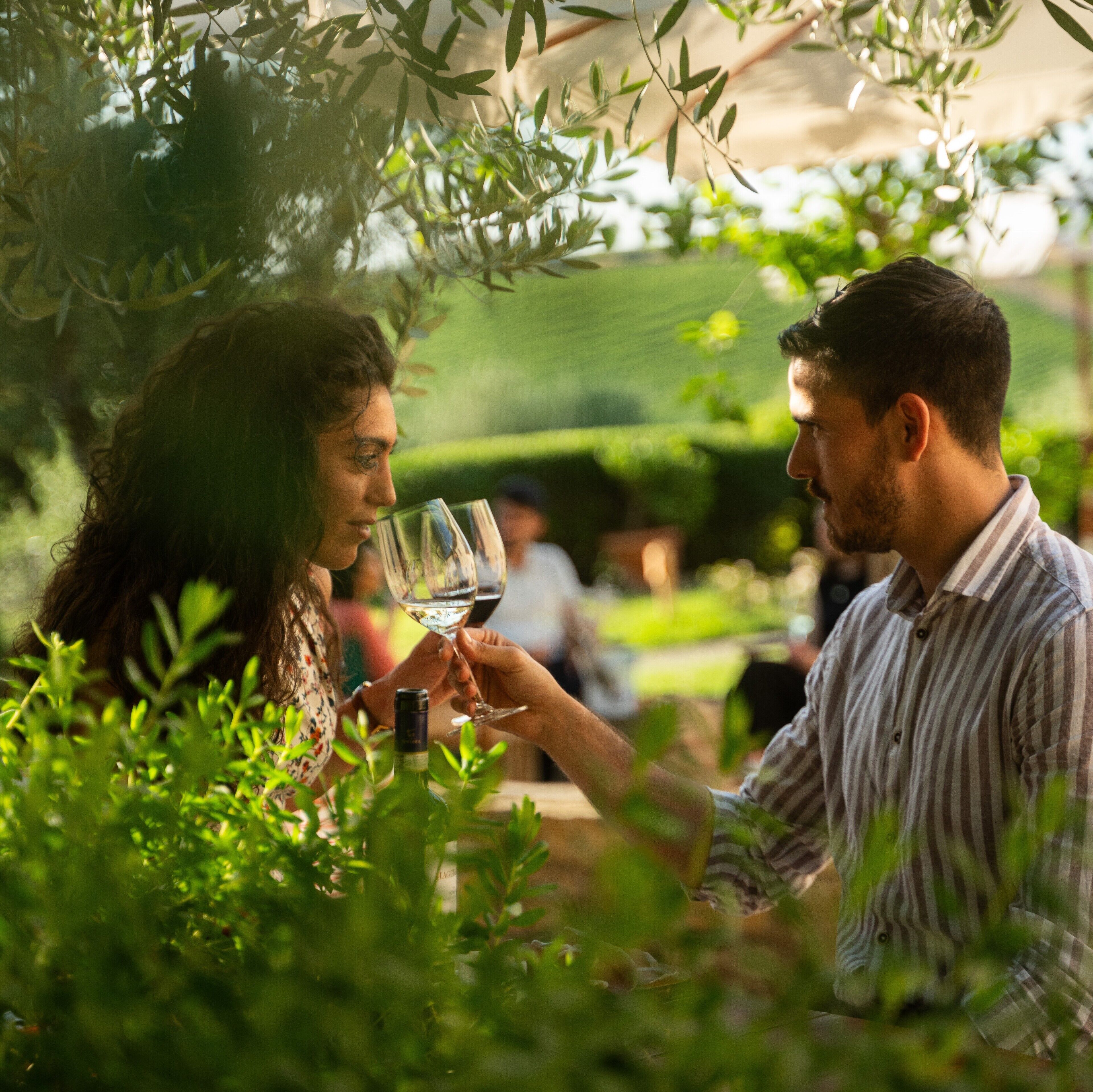 A couple toasting with wine glasses in a garden setting.