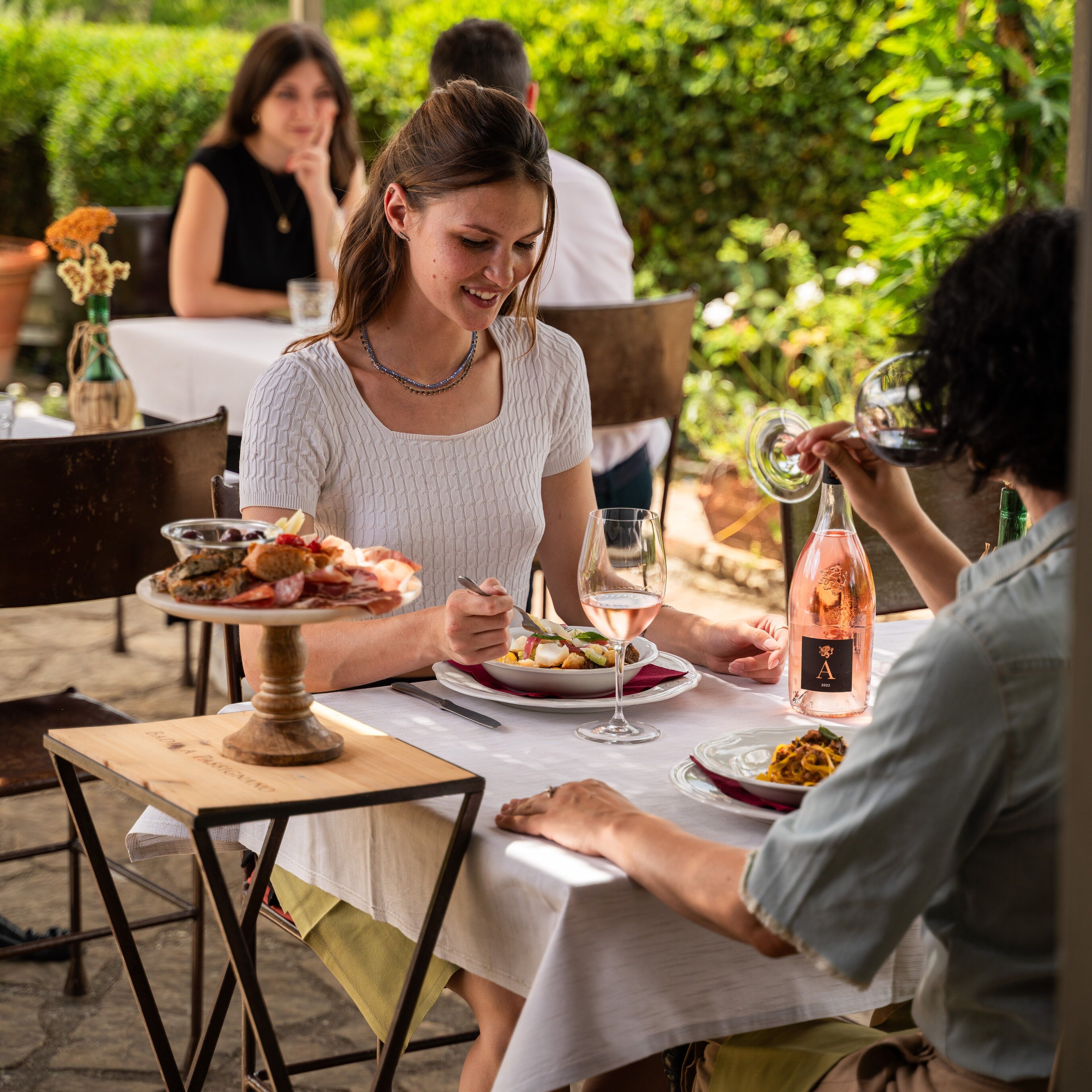 A dining table with plates of food, a wine glass, and a bottle of wine.