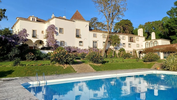 A large, white building with a swimming pool in the foreground.