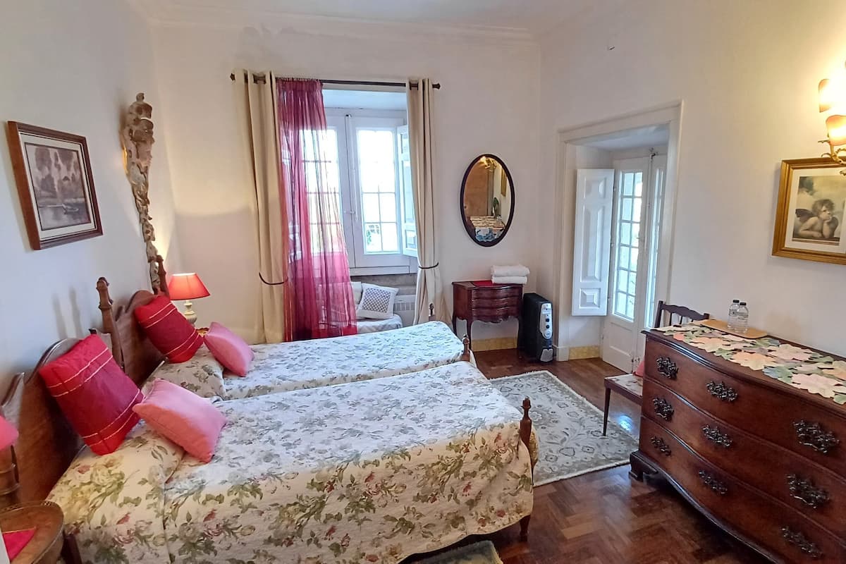 Een slaapkamer met twee bedden, een kaptafel, een spiegel en een kroonluchter.