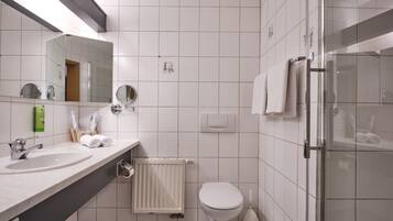 Un baño moderno con lavamanos, espejo, inodoro y ducha.