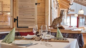 Interior de restaurante con paredes de madera, una mesa preparada para comer y una figurita de conejo en la barra.