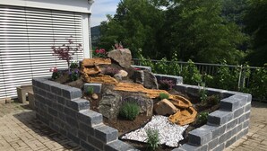 A landscaped garden with a rock feature, stepping stones, and various plants. - Hotel am Hochrhein (Bad Saeckingen)