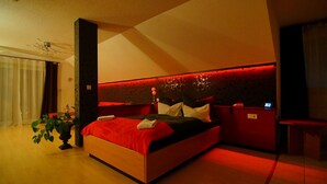 A modern bedroom with a large bed, a bedside table, a nightstand, and a potted plant. - Hotel am Hochrhein (Bad Saeckingen)
