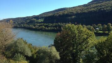 Une rivière bordée d’une végétation luxuriante et entourée de collines.