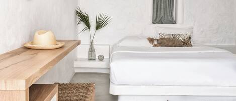 A bedroom with a bed, bedside table, mirror, and a small window.