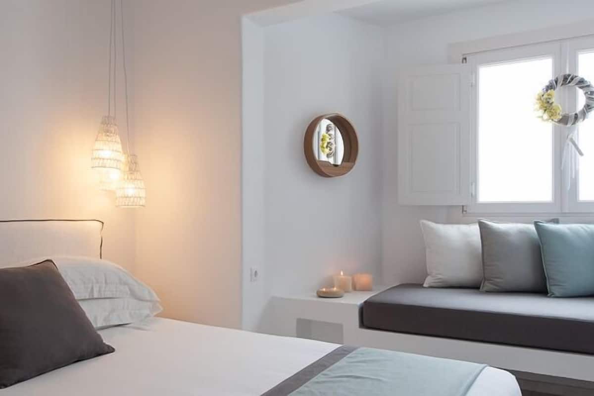 A bedroom with a bed, bedside table, and a window with a wreath.
